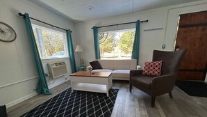 Een kamer met een bank, een stoel, een bijzettafeltje en een kamerbreed tapijt met dessin.