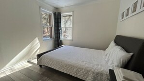 Een slaapkamer met een bed, een raam en uitzicht op bomen.
