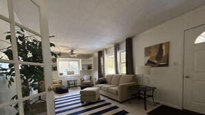 Ein Wohnzimmer mit einer Couch, Hocker und einem Streifenmuster-Teppich.