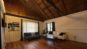 A spacious living room with wooden floors, a dark sofa, a white sofa, and a coffee table. - 2 BR, walk to beach, volleyball (Sanilac Township)
