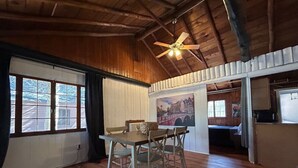 A spacious room with wooden floors, a dining table with chairs, a ceiling fan, and a large window with curtains. - 2 BR, walk to beach, volleyball (Sanilac Township)