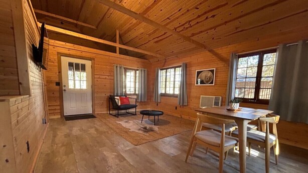 L'intérieur d'un chalet en bois comprend un coin repas, un canapé et une cheminée.