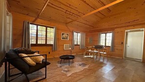 Un salon spacieux doté d’un plafond en bois, d’un canapé, d’une table basse, d’un tapis et d’un coin repas avec des chaises.