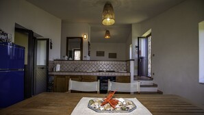 Une cuisine avec une table à manger pour deux personnes, un réfrigérateur bleu et un luminaire suspendu.