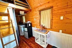 A compact kitchen with a refrigerator, a microwave, and a small table with a chair.