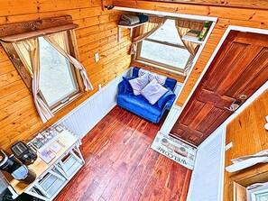 Una cabina compatta con un divano blu, pareti in legno e un angolo cottura piccolo.