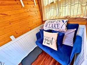 Una stanza accogliente con un divano blu, due cuscini decorativi e un pavimento in legno.