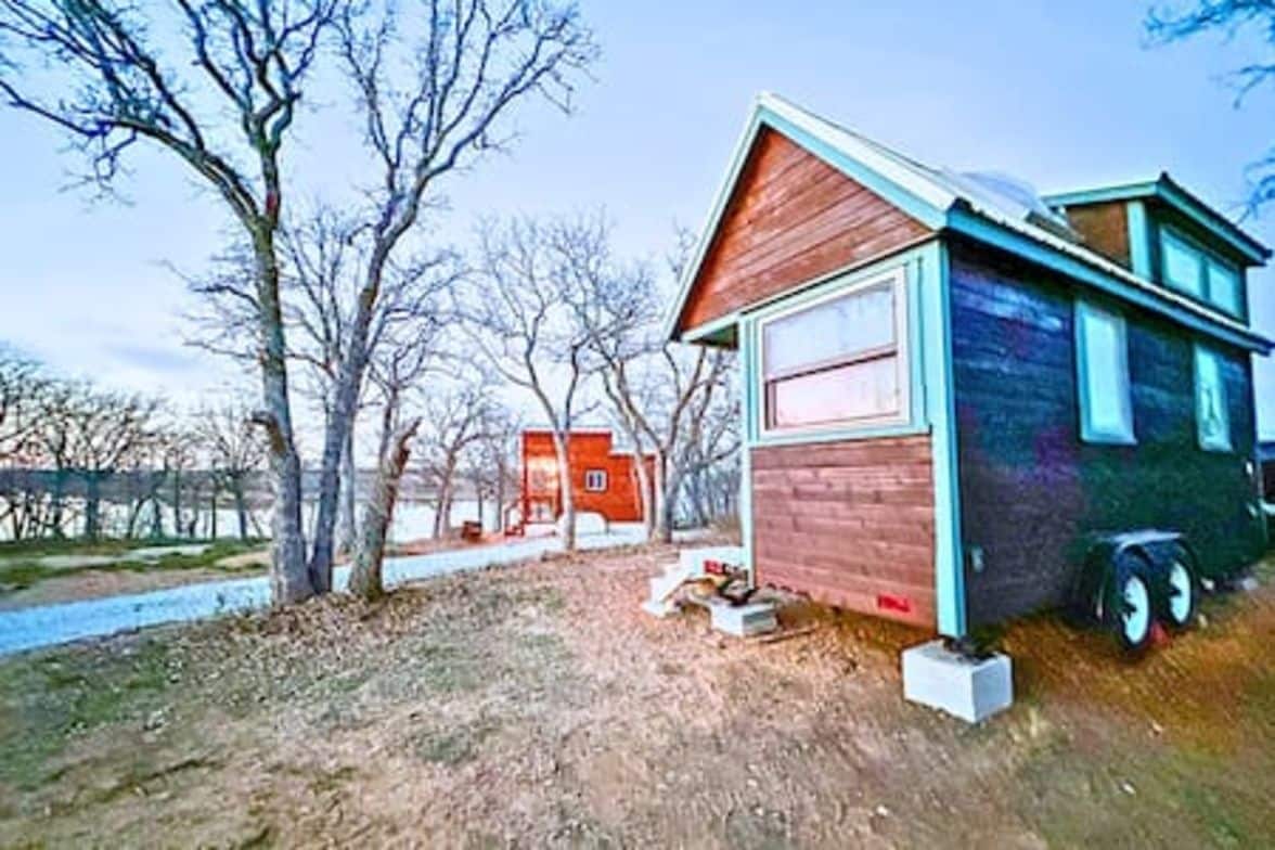 A small, single-story wooden cabin with a sloped roof, a visible window, and a door.