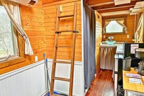 A wooden cabin interior with a wooden ladder, a window with curtains, a sink, and a counter with items on it. - 2  Lakefront, Comfortable Bed, Great Fishing (Eastland)