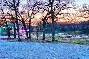 A gravel area with trees and a small building with a purple light.