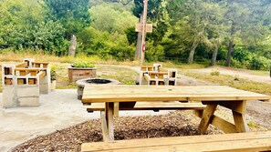 A picnic area with wooden benches and a fire pit.