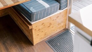 Un interior acogedor con un banco de madera, asientos acolchados y una ventana con cortinas.