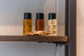 Drie flessen PRIJA haarverzorging staan op een plank.