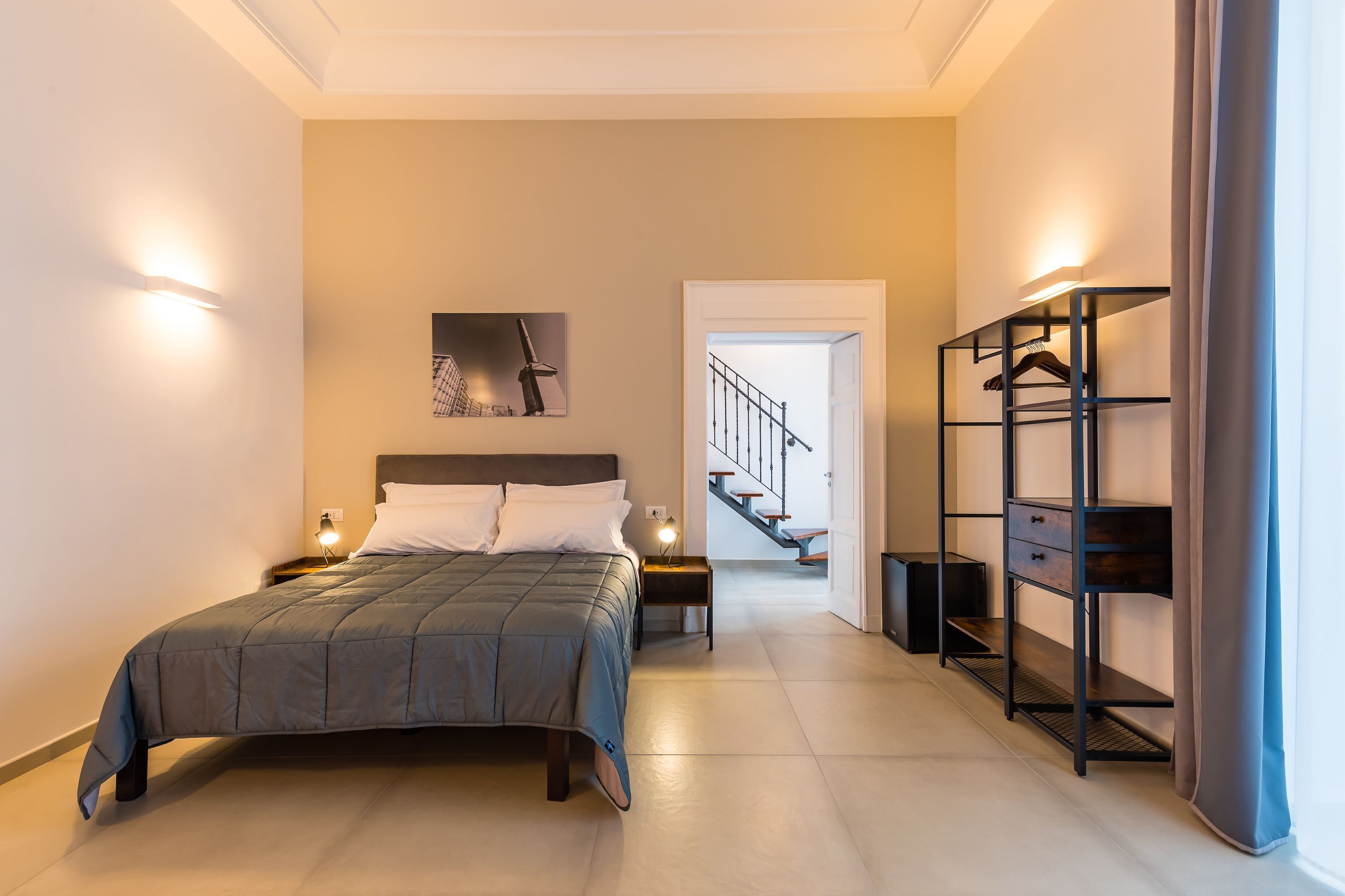 Un dormitorio moderno con una cama grande, mesitas de noche, un armario y una escalera que sube a otro nivel.