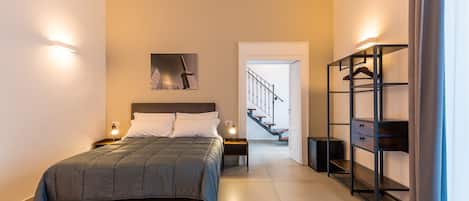 Un dormitorio moderno con una cama grande, mesitas de noche, un armario y una escalera que sube a otro nivel.