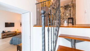 A modern staircase with a metal railing and wooden steps, leading to a room with a bed and a TV. - Residenza Partanna by Napoliapartments (Naples)