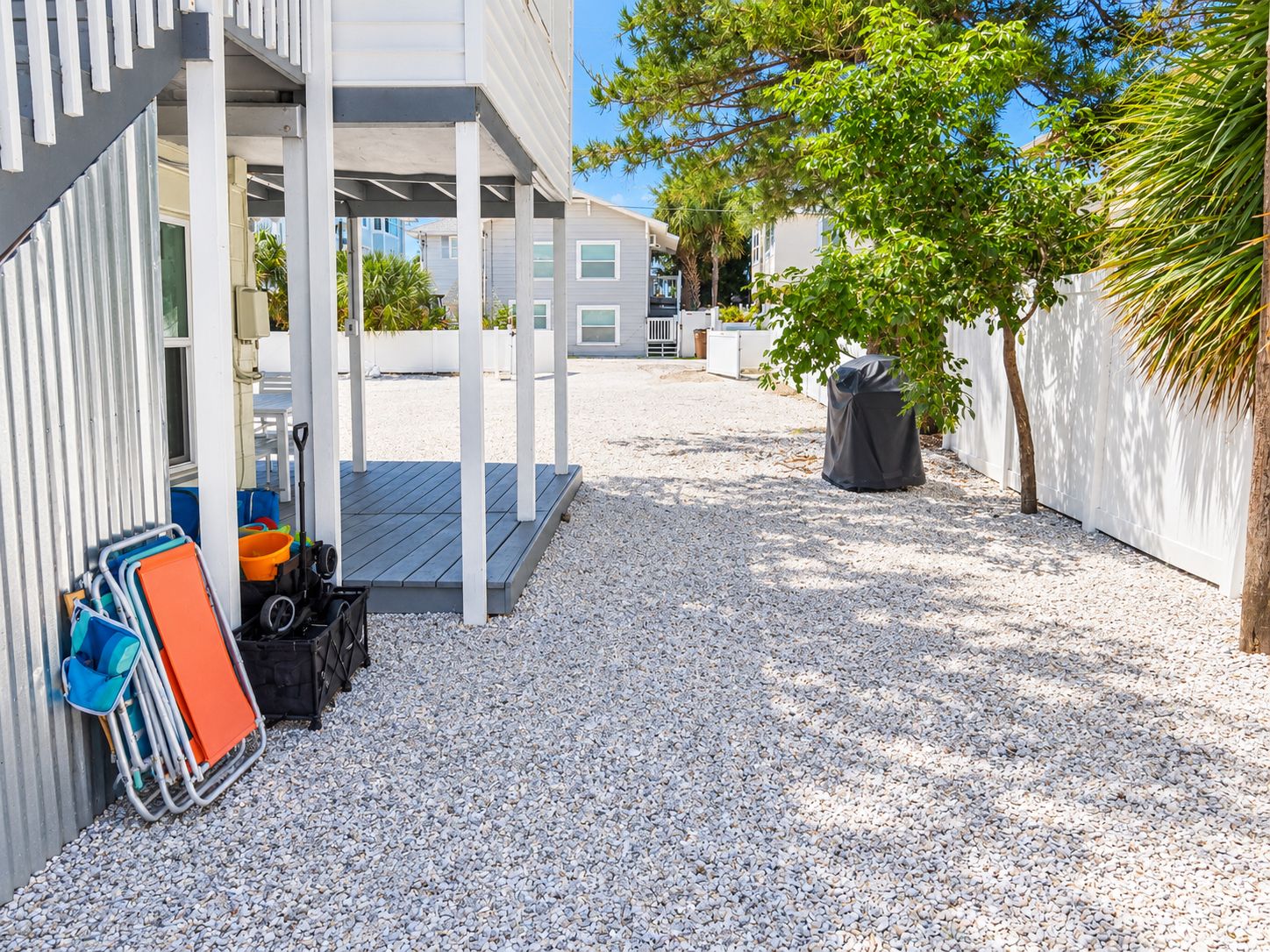 Un espace extérieur abrité avec un sol en gravier, un coin salon couvert et une poubelle.
