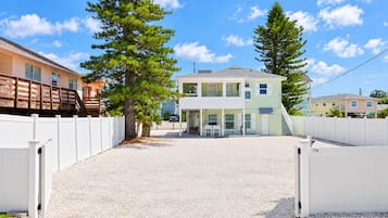 Ein zweistöckiges Haus mit überdachter Veranda und einem Schotterweg.