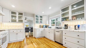Een moderne keuken met witte kasten, houten vloeren en een centraal eiland.