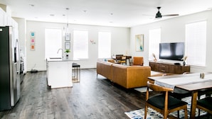 A modern kitchen with white cabinets, a black refrigerator, and a dining area with a wooden table and chairs. - Mid-Century Modern Home is 10 minutes from Downtown Houston (Houston)