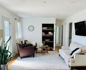 A living room with a brown leather sofa, a white sofa, a coffee table, and a bookshelf. - Oldtown Guesthouse (Oldtown)