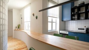 Une cuisine moderne avec un plan de travail en bois aux lignes courbes, des chaises vertes et une cuisinière intégrée.