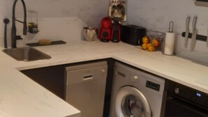 Eine kleine Küche mit Waschmaschine, Spüle und Mikrowelle.