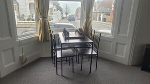 A corner room with a large window, a dining table with chairs, and a view of the street outside. - Beautiful 1-bed Apartment in Ramsgate (Ramsgate)