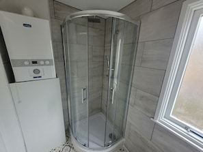 A glass-enclosed shower with a control panel, tiled walls, and a window. - Beautiful 1-bed Apartment in Ramsgate (Ramsgate)