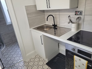 A compact kitchen with a stainless steel sink, a black stovetop, and a dishwasher. - Beautiful 1-bed Apartment in Ramsgate (Ramsgate)