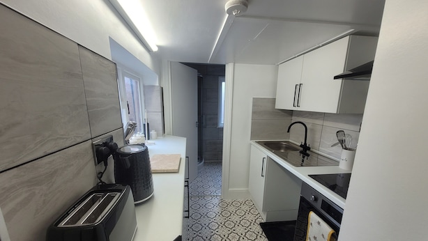 A modern kitchen with a toaster, sink, and patterned floor tiles. - Beautiful 1-bed Apartment in Ramsgate (Ramsgate)