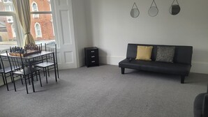 A living room with a black sofa, a chessboard, and a small black side table. - Beautiful 1-bed Apartment in Ramsgate (Ramsgate)