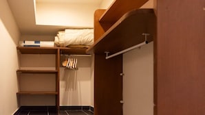 A compact room with a bunk bed, a small shelf, and a wardrobe.