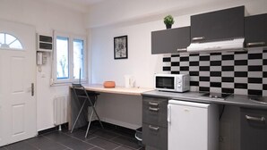 A compact kitchen with a microwave, a small refrigerator, and a checkered backsplash.