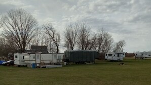 A grassy field with several RVs and trailers parked. - Relax and enjoy nature at the spacious North branch get away. 39 acres available (Hesperia)
