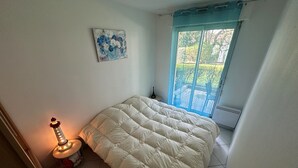 Une chambre à coucher avec un lit, une lampe, un tableau et une fenêtre donnant sur un paysage verdoyant.