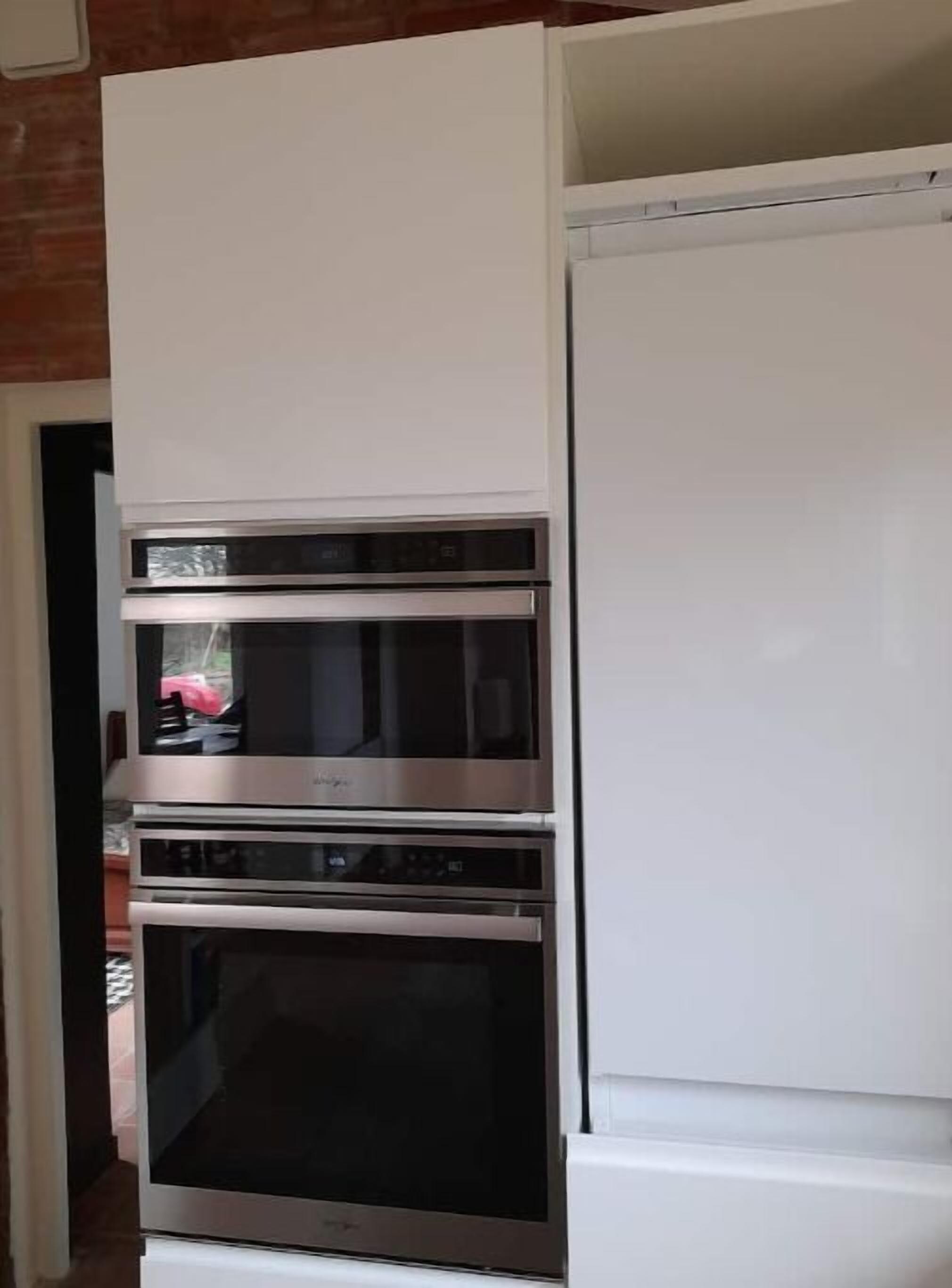 Una cocina con horno empotrado y un refrigerador blanco.