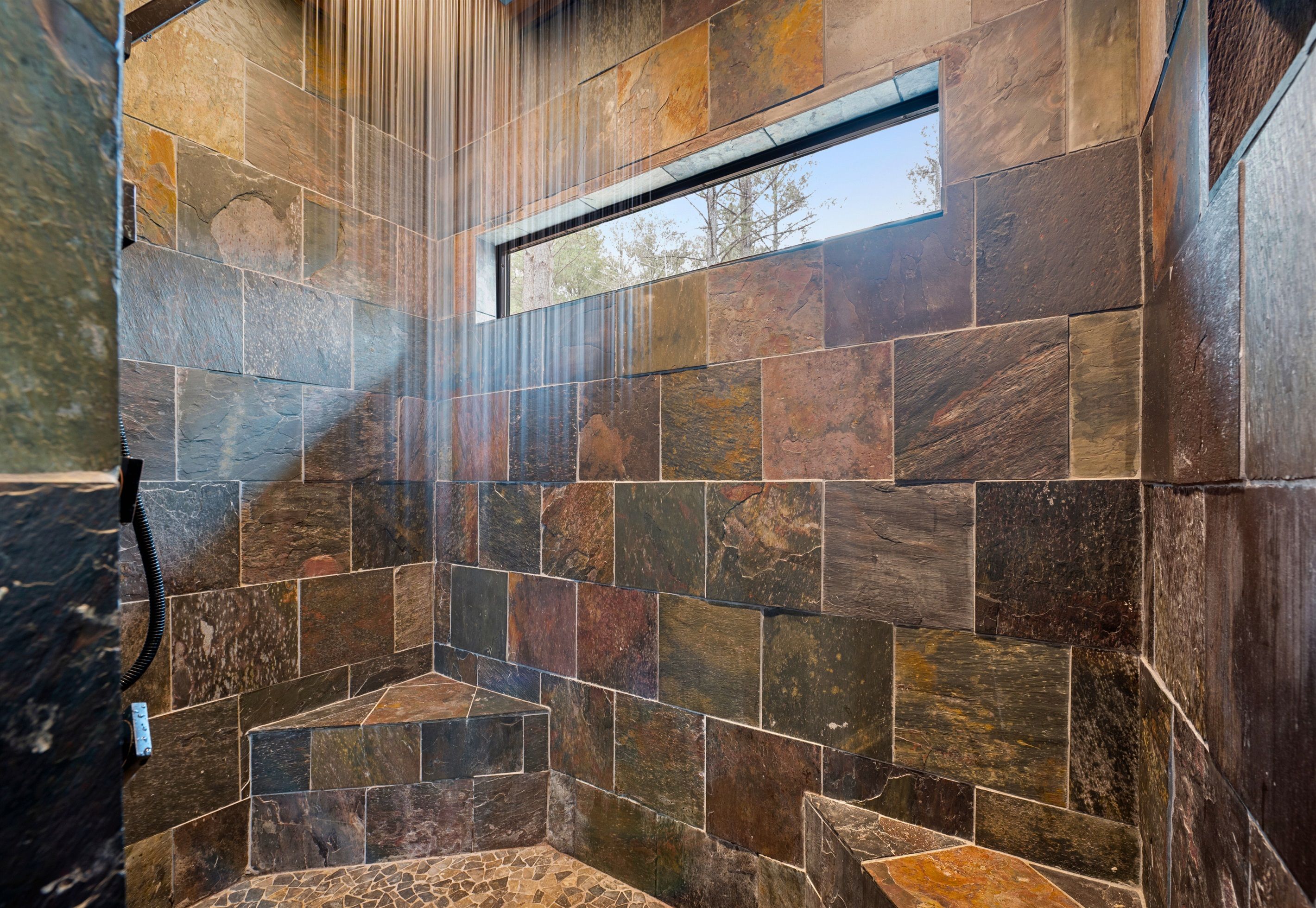 Ducha con pared de piedra y ventana.