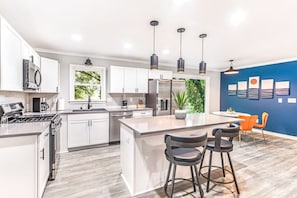 A modern kitchen with white cabinets, a central island with bar stools, and pendant lighting.