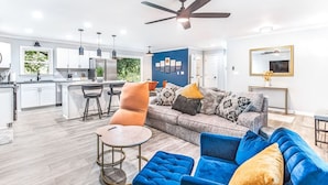 A modern living space with a kitchen, dining area, and a large sofa with multiple cushions.