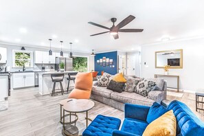 A modern living space with a kitchen, dining area, and a large sofa with multiple cushions.