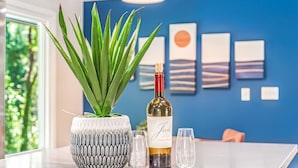 A table with a potted plant, a wine bottle, and two glasses.