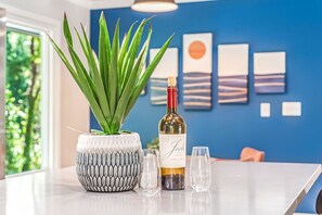 A table with a potted plant, a wine bottle, and two glasses.