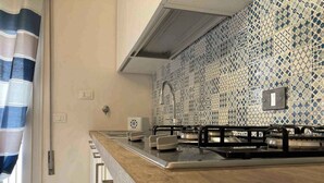 A kitchen with a modern design, featuring a stainless steel countertop, a gas stove, and a patterned backsplash. - Holiday apartment with balcony and air conditioning (Rosolina Mare)