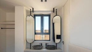 Een moderne badkamer met een groot raam, twee wastafels en twee spiegels.