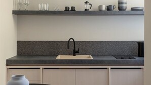 Een moderne keuken met een granieten aanrecht, een zwarte kraan en een witte vaas op een zwarte tafel.