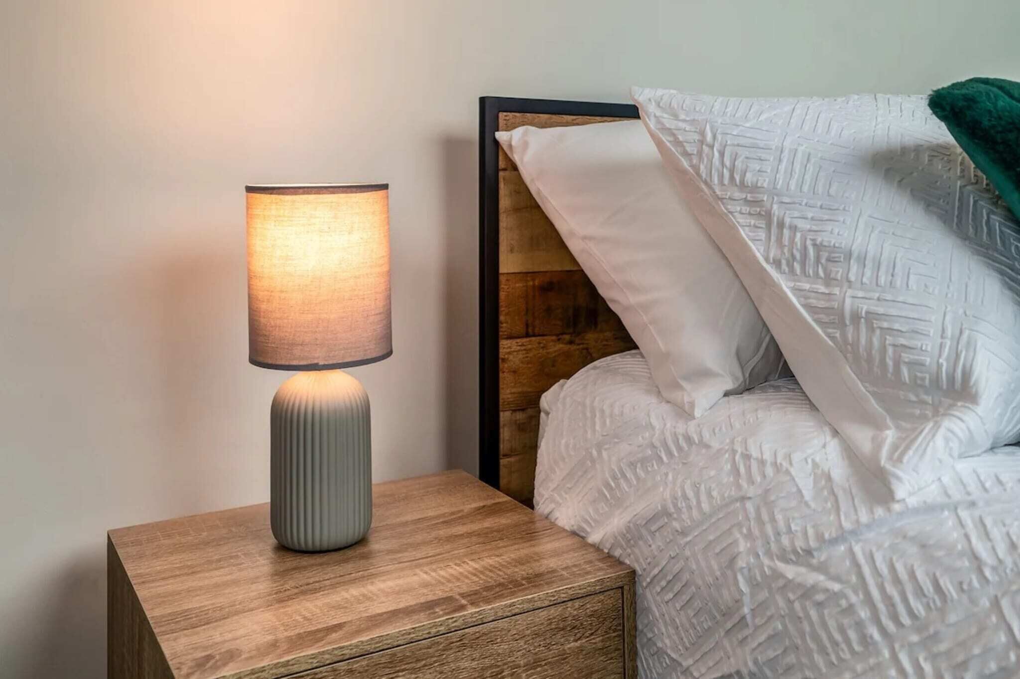 Ein Nachttisch mit Lampe und ein Bett mit Kopfteil.
