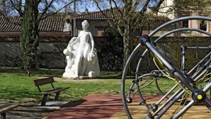 A park with a statue, a bicycle, and a bench.