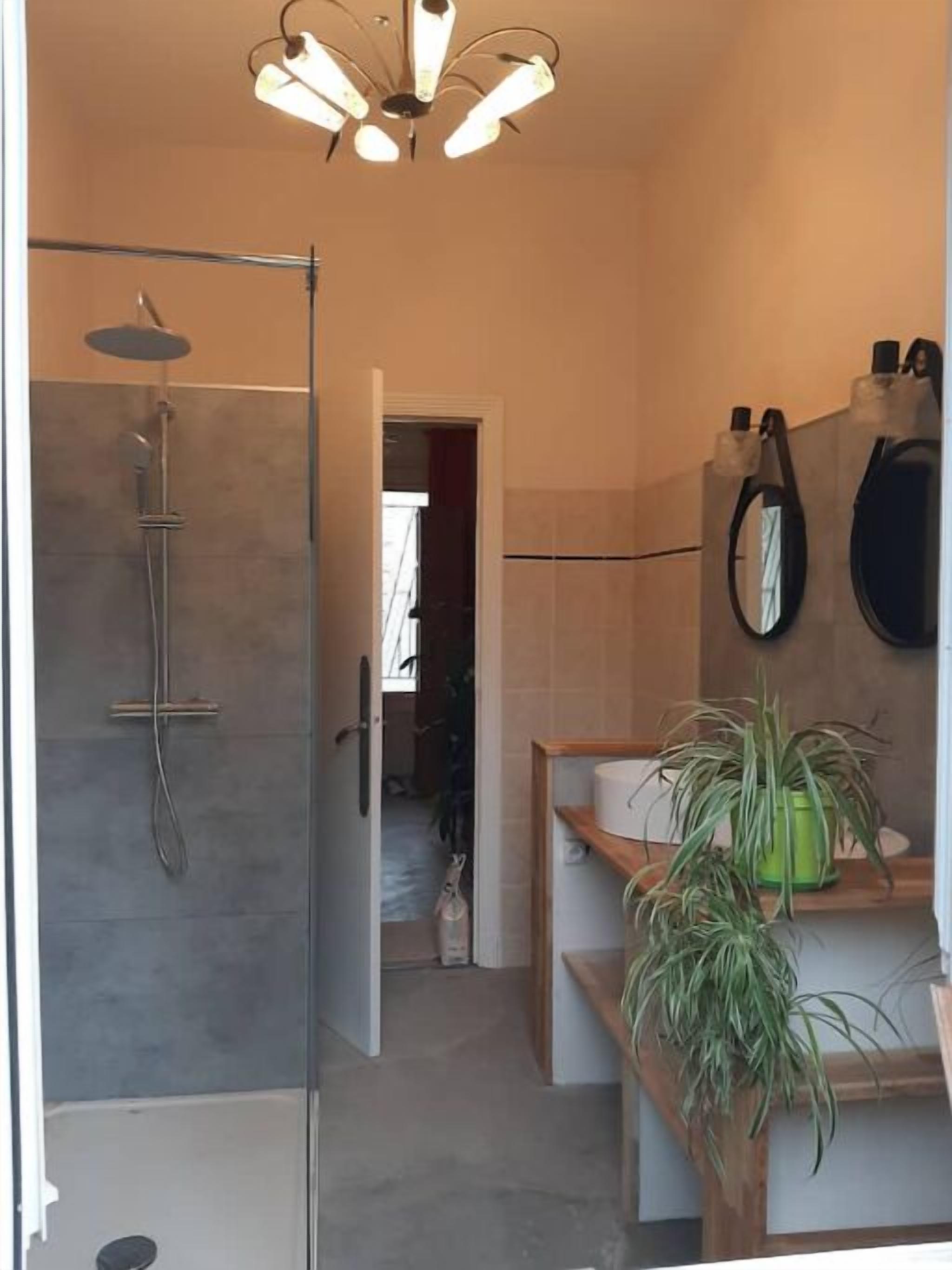 Une salle de bain moderne avec une douche, des toilettes et un lavabo. On peut voir une plante en pot sur le comptoir du lavabo.