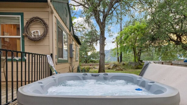 Ein Whirlpool in einem Hinterhof mit einer Holzterrasse, einem Metallgeländer und einem Haus mit einem Kranz an der Wand.
